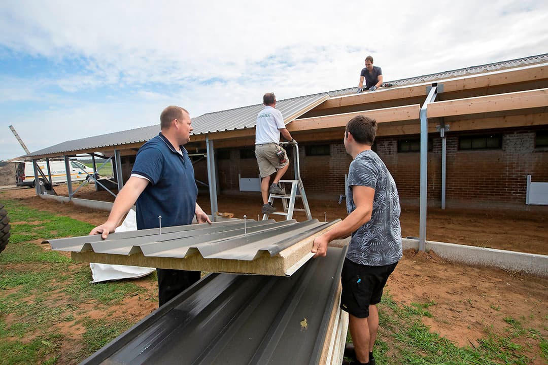 De bouw van de overdekte uitlopen is na de bouwvak op maandag 22 augustus hervat. Bedrijfsopvolgers Marco (l.) en Stephan Feijen helpen mee met de bouw. - Foto's: Hans Banus