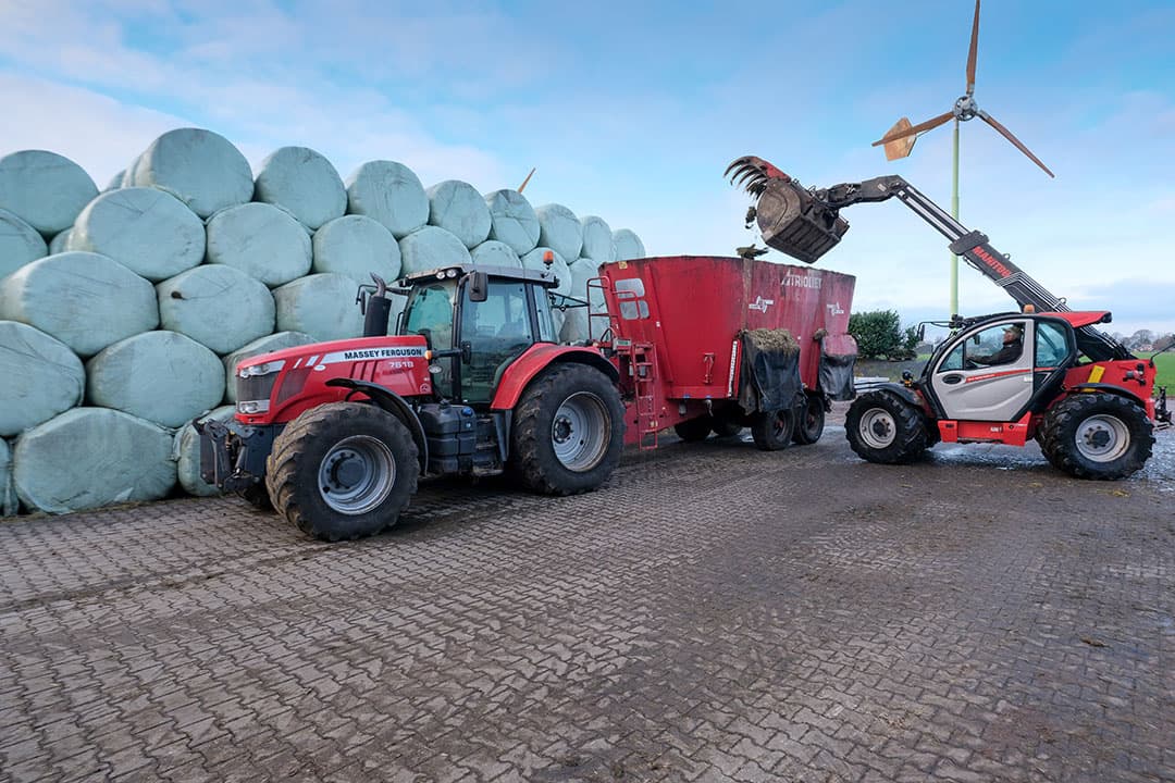 De geknipte balen worden geladen in de voermengwagen. Zowel het uithalen, knippen als laden wordt met de verreiker uitgevoerd.