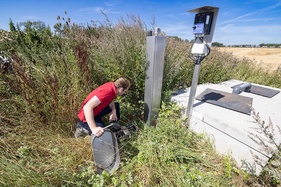 Laurens den Hartigh bij pompput en stuwput, waarin water vanuit de sloot kan worden opgezet tot een gewenst grondwaterpeil.  Meetdrains in het perceel sturen de vlotter aan. - Foto's: Peter Roek