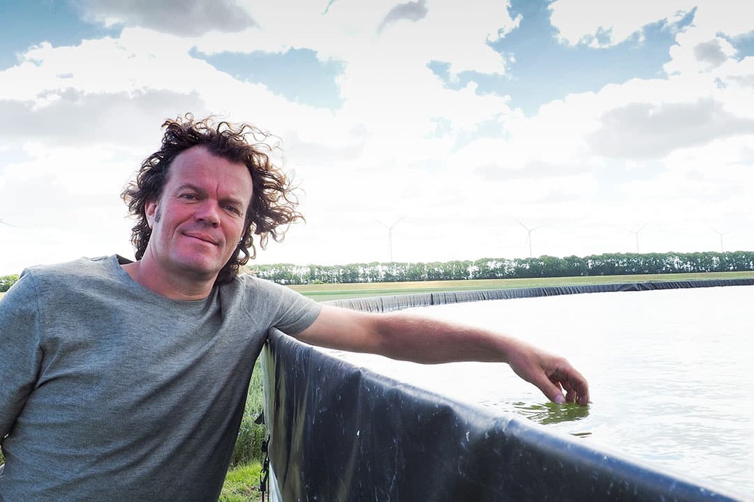 Klaas Schenk bij zijn 1.000 kuub waterbuffer die gebruikt wordt voor druppelirrigatie. - Foto: Marga van der Meer