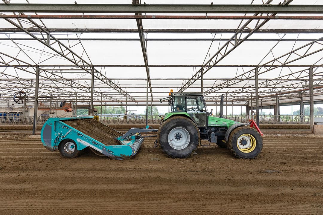 Floren de Vries rijdt met de BeddingCleaner door de stal; mest wordt uit het zand gezeefd en gaat dagvers de stal uit.