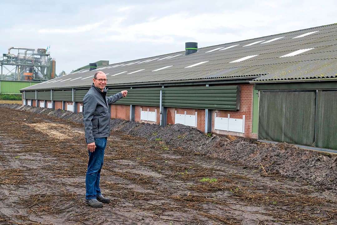Aan deze vleeskuikenstal wordt een 9 meter brede scharrelruimte gebouwd, zo laat Martin Nijkamp zien. Op de achtergrond is de naburige asfaltcentrale zichtbaar. De ondernemers vertellen op hun Facebookpagina regelmatig over hun werkzaamheden.