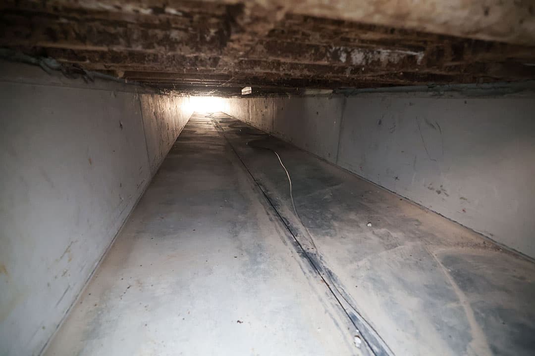 Een kijkje in het mestkanaal onder het roostergedeelte van de stal. De vloer heeft een v-vorm, zodat de urine naar het midden loopt en wegstroomt via de geleider.