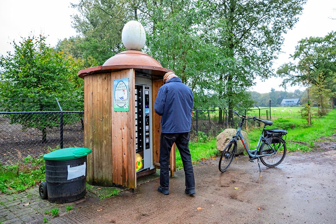 Beeld van de eierautomaat. De ondernemers moeten de automaat regelmatig bijvullen. In februari 2024 wordt de huisverkoop aan de weg gemoderniseerd, met een nieuw huisje. Klanten kunnen lege eierdoosjes deponeren in de ton, naast de automaat.