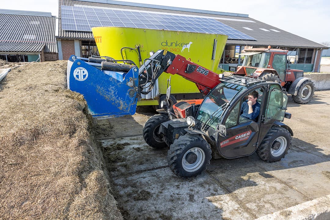 Tjeu van Beek laadt de voermengwagen met gras bij de graskuil. Dit is het laatste deel van de op elkaar gekuilde eerste, tweede en derde snede.