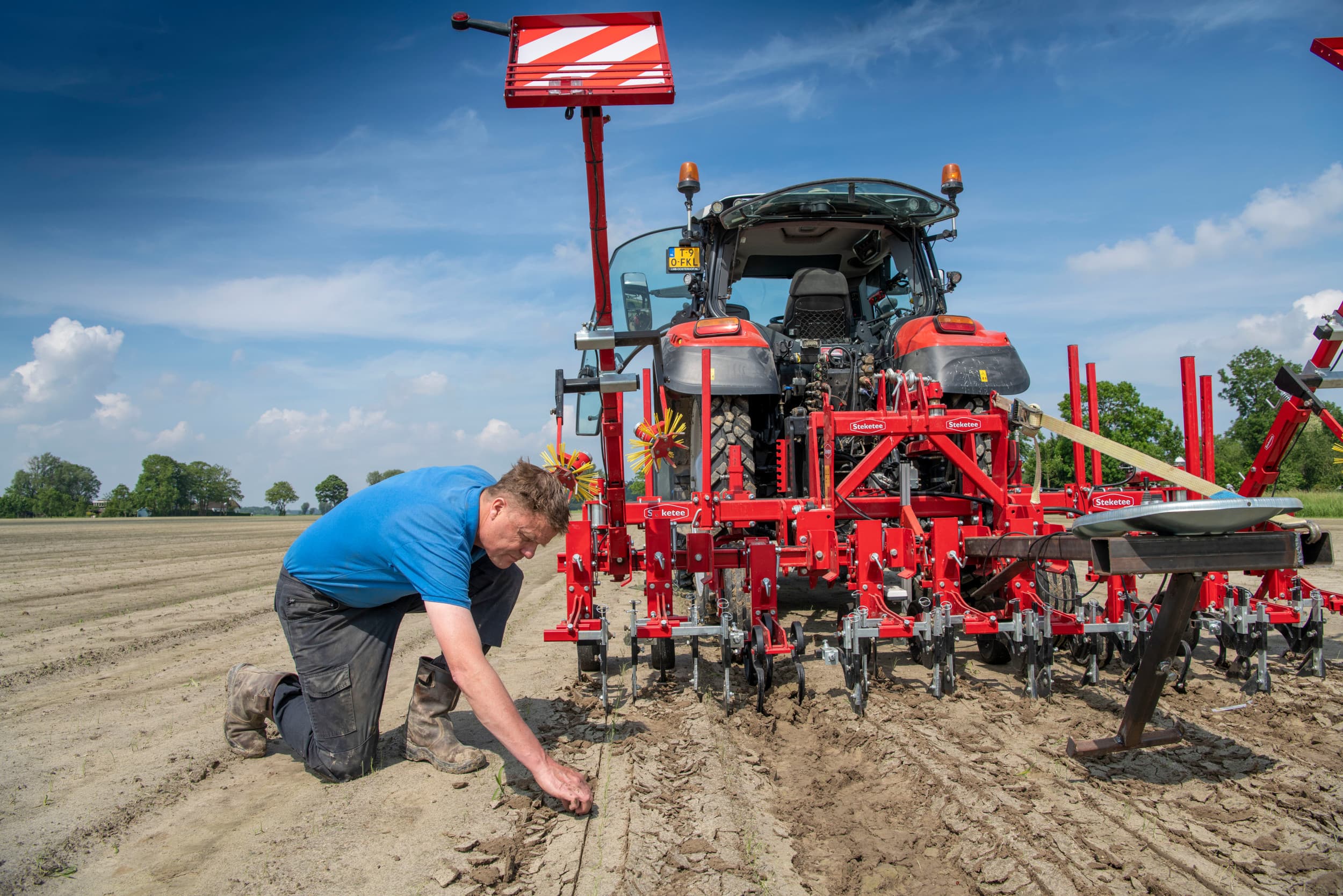 Achterop de schoffel heeft Gesink een stoeltje gemaakt om met de hand de schoffel bij te sturen als dat nodig is. Maar dan zijn wel twee personen nodig om te schoffelen. Als er geen plensbui was geweest (uien onder het zand) en de uien wat groter zijn dan herkent de camera de uienrijen wel goed.