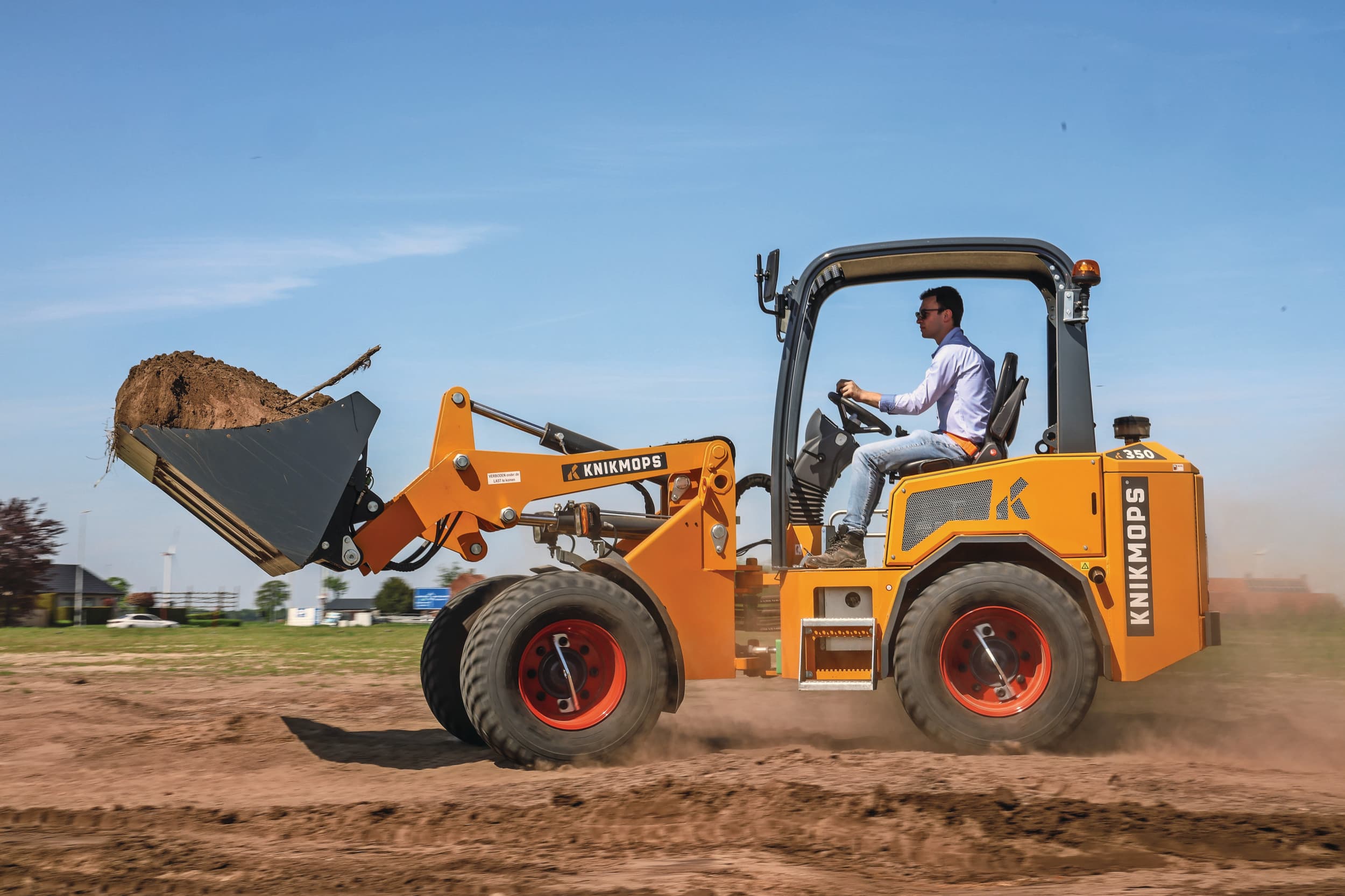 Het Belgische Knikmops breekt met minishovel KM350 met zijn eigen beginselen en stapt nieuw in het 3,6-tons segment. Meer capaciteit is een vraag uit de veranderende markt. De nieuwkomer is duidelijk nieuw ontwikkeld met Z-kinematiek en een vast knikpunt. En tegelijk nog steeds herkenbaar Knikmops, met wielmotoren en de compacte achterzijde. – Foto’s: Matthijs Verhagen