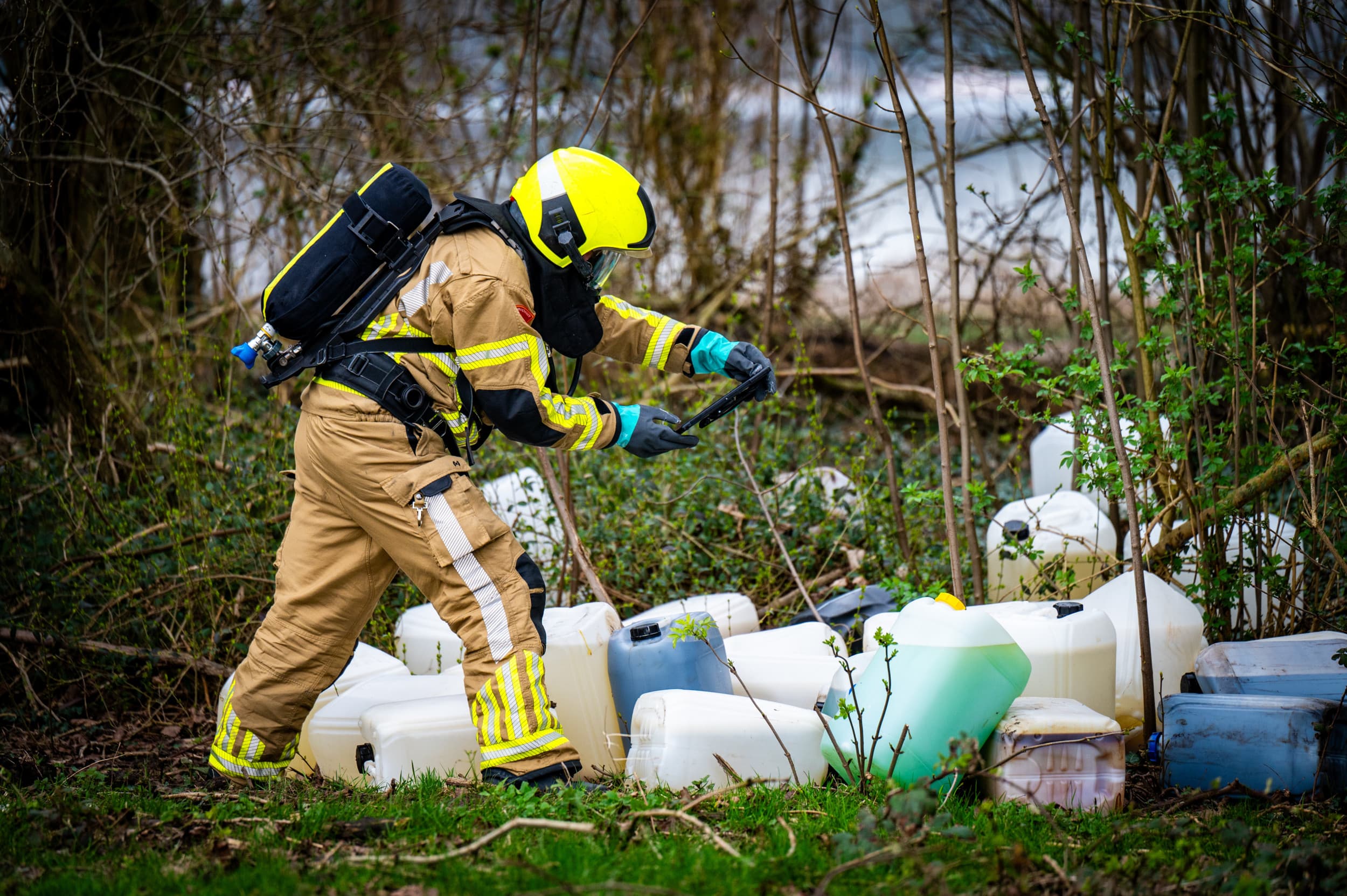 Brandweerlieden onderzoeken een lading drugsafval dat gedumpt is. Foto: ANP