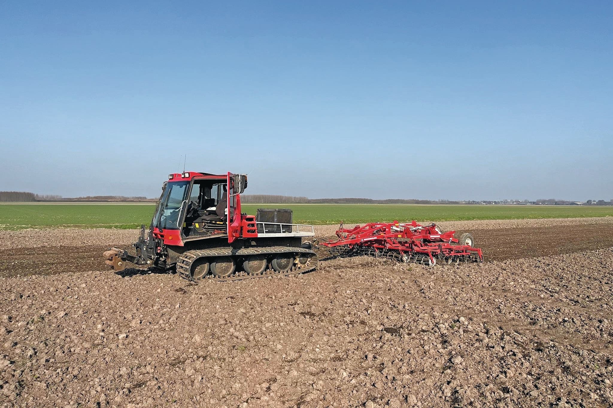 Loonwerker Nic van Dorp is altijd op zoek naar mogelijkheden om schade aan de bodem te verminderen. Met 3.200 kg is de PistenBully lichter dan de trekker die normaal voor de snel-eg staat. De rupsbanden verdelen het gewicht van de machine beter tijdens het klaarleggen van het uienland. – Foto’s: Nic van Dorp