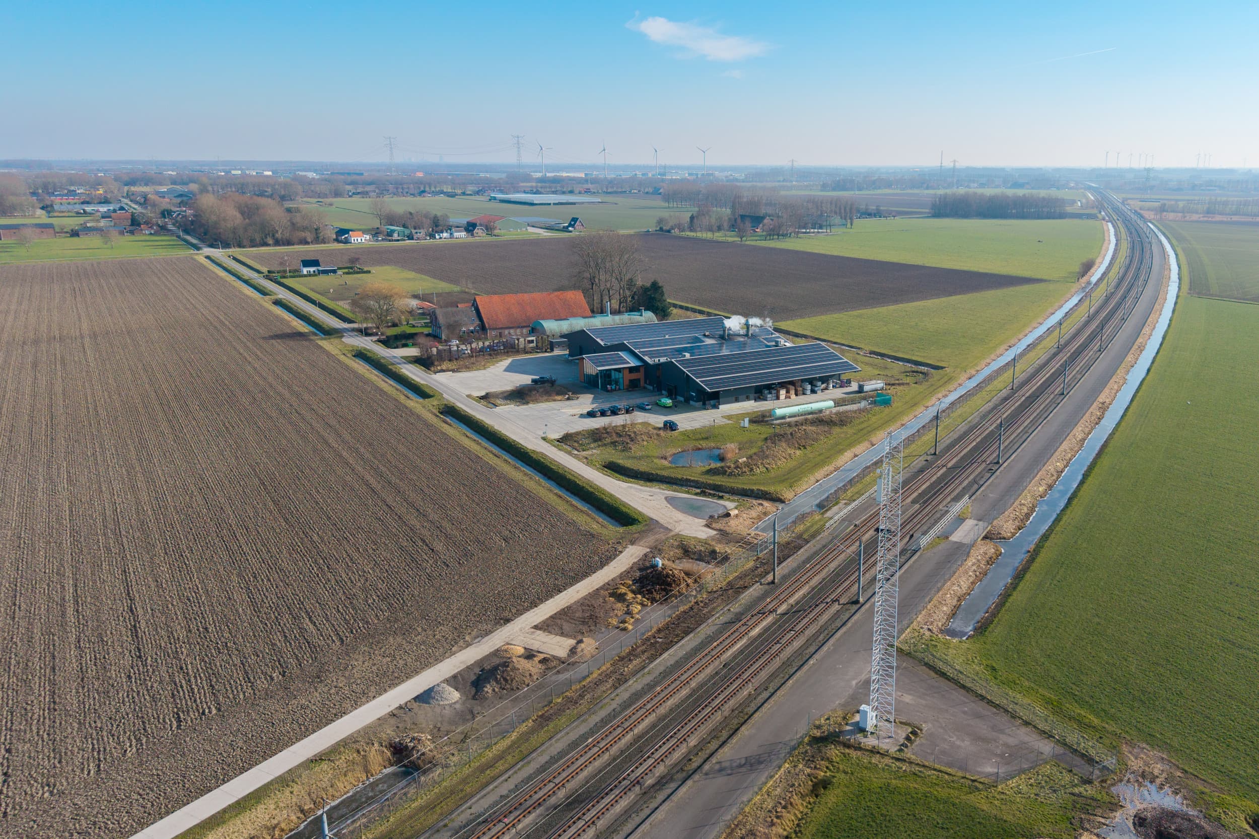 De Hoeksche Hoeve. Het bedrijf ligt pal naast hogesnelheidsspoorlijn Schiphol-Antwerpen (HSL). Deze spoorlijn doorkruist het gebied en komt ook langs het grote gemaal waar het water van de polder afgevoerd wordt. Goed zichtbaar is het water langs de spoorlijn; een mogelijke ‘watersnelweg’ om water af te voeren. Foto: Peter Roek