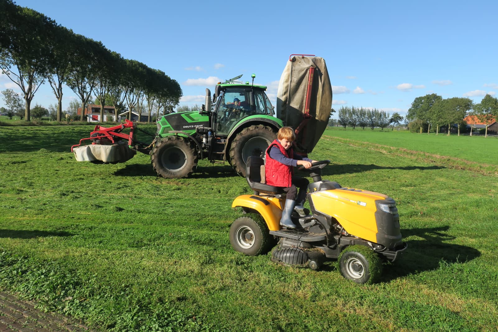 Gras maaien voor het huis met de trekker en de gazonmaaier in de middag van 2 oktober. Kleinzoon Bram op de gazonmaaier, kleinzoon Johannes op de trekker. - Foto: Oma Noordergraaf