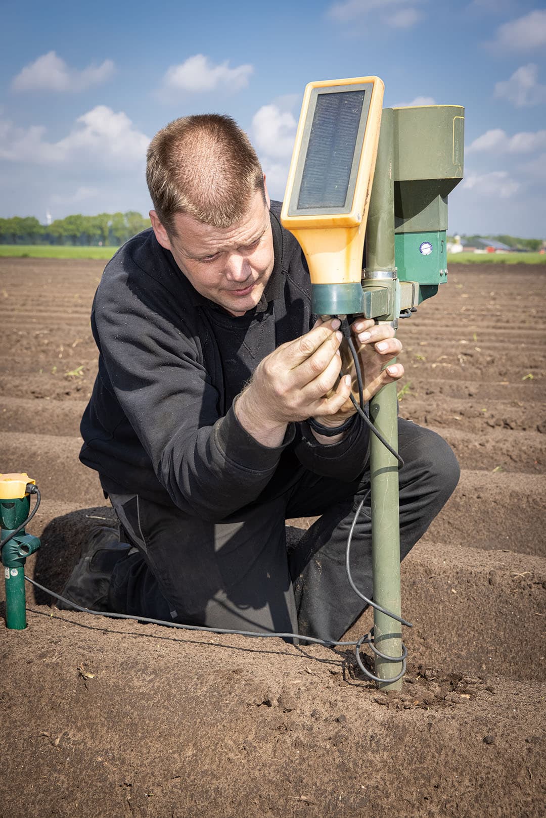 Van den Borne plaatst vochtsensoren op een aardappelveld achter zijn boerderij.
