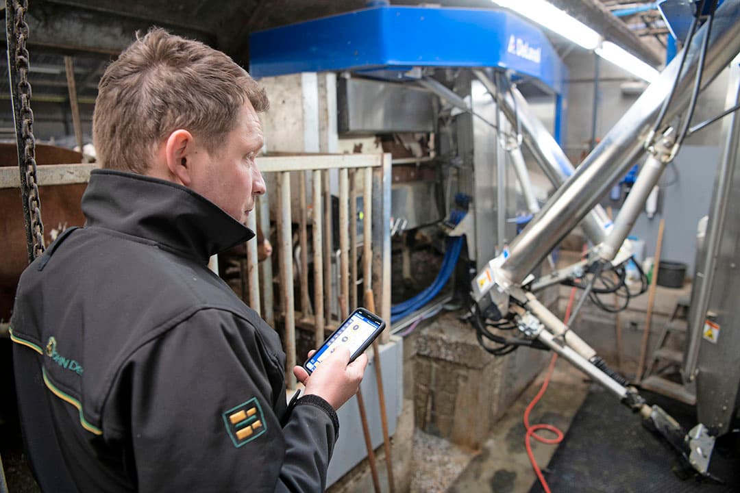 Hans Broekhuijse bij de DeLaval VMS V300 melkrobot met twee boxen. Op zijn smartphone ziet hij hoe vlot elk kwartier wordt gemolken. - Foto's: Mark Pasveer