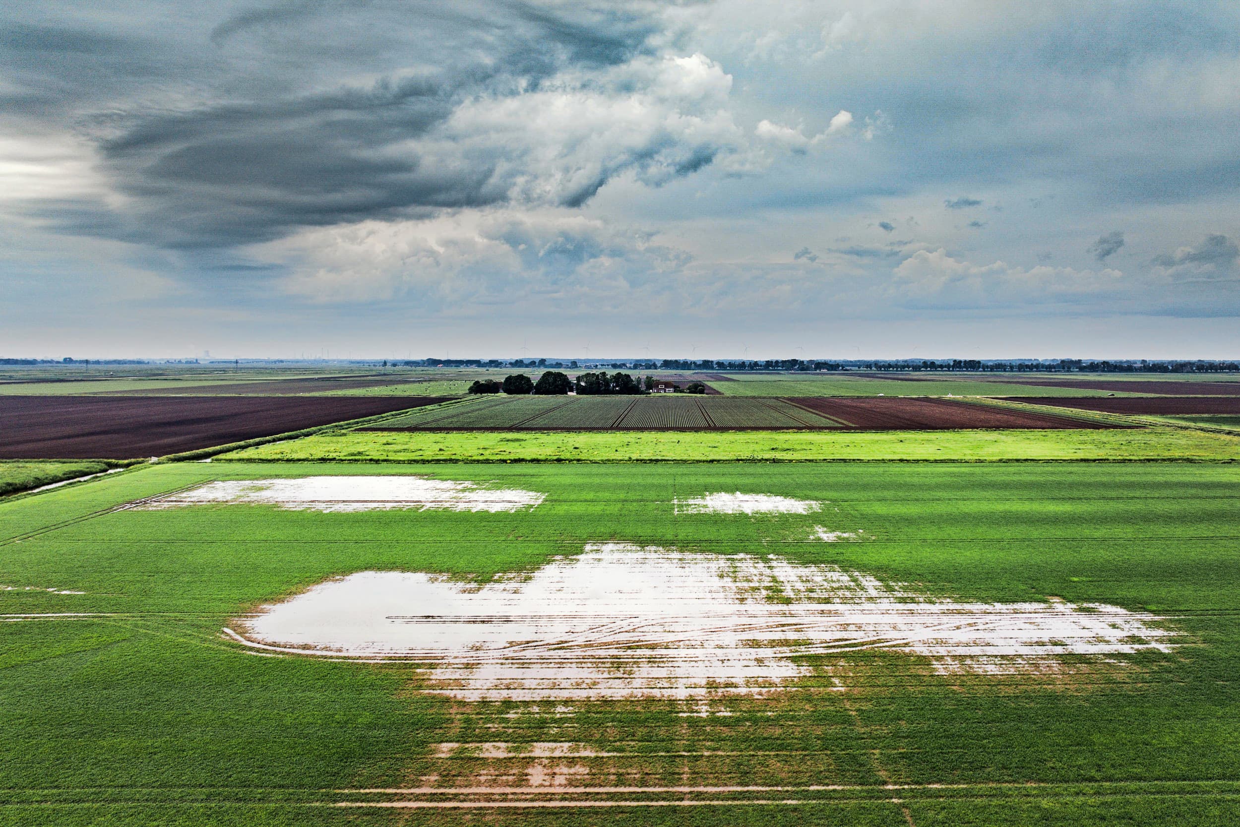 Dreigende luchten boven een nat polderlandschap. – Foto: ANP