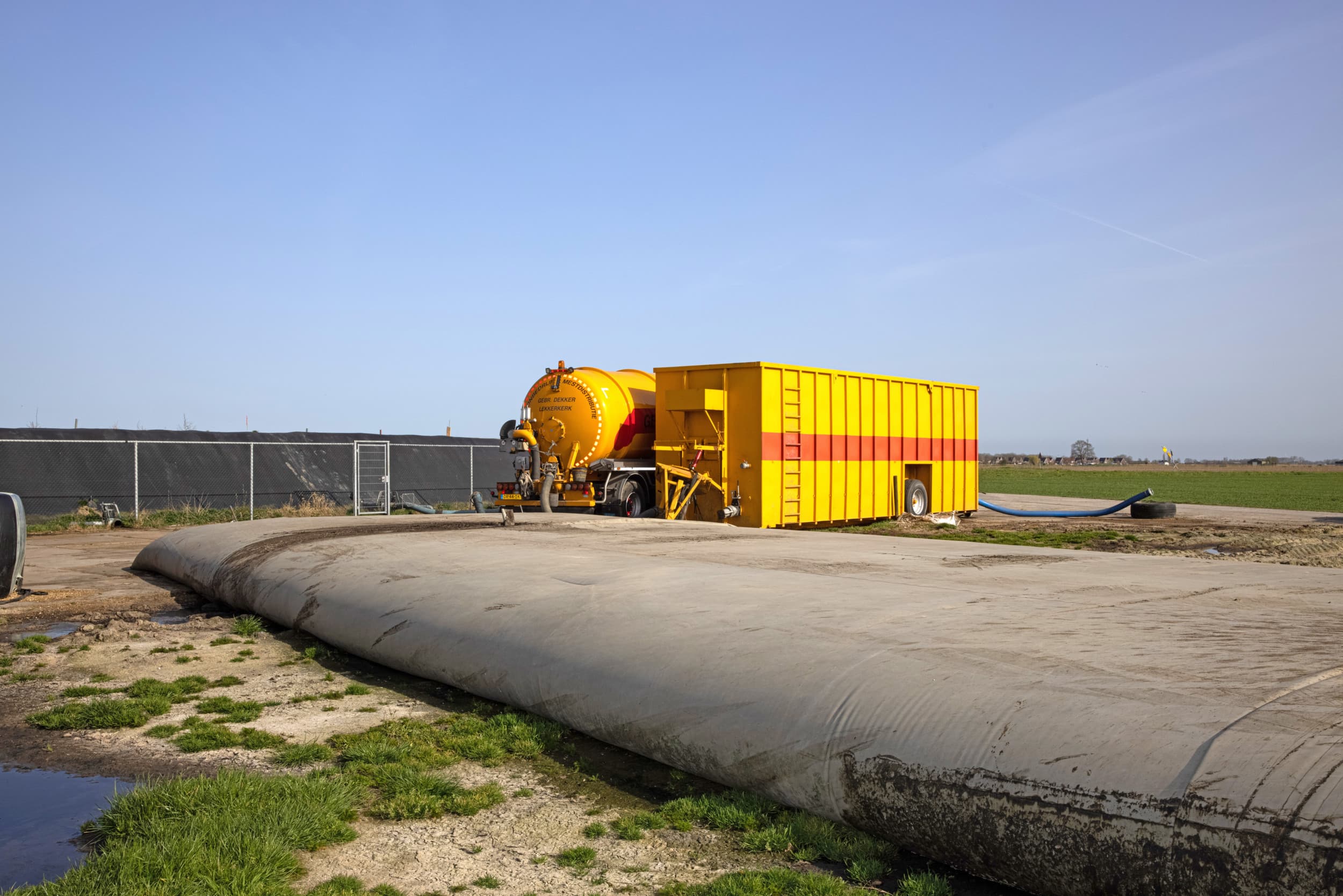 Een loonbedrijf pompt mest uit een mestzak in de tankwagen. Mestzakken zijn zeer geschikt voor extra mestopslag. Op de achtergrond een foliebassin, een relatief goedkope oplossing voor opslag van grotere volumes mest. – Foto: Peter Roek