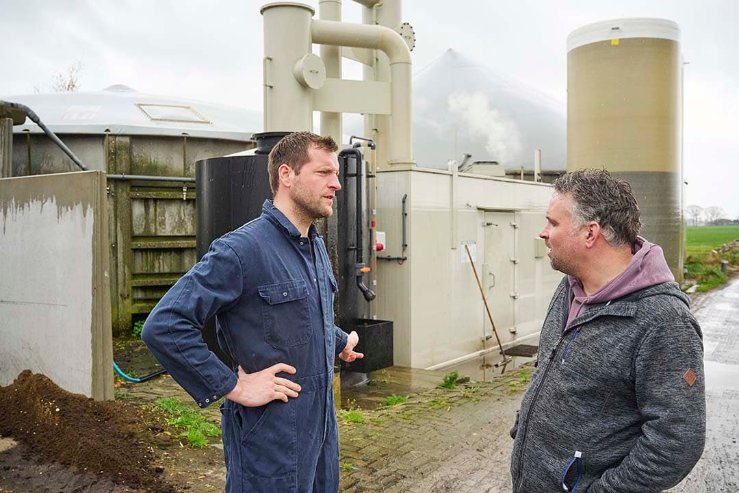 Akkerbouwer Bart Peters (rechts) werkt samen met melkveehouder Teun Wientjes. Op de achtergrond de Jumpstart-mono-mestvergister en stikstofstripper van Wientjes. De Brabanders willen de nieuwe meststromen hieruit zo goed mogelijk benutten met minder N-verliezen. - Foto: Van Assendelft