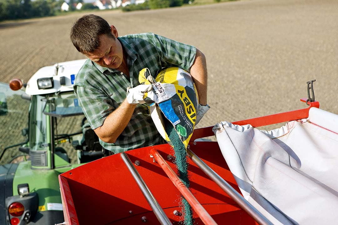 Dirk Wendel, operationeel manager bij Rehhütte Boerderij, vult de zaaimachine die aan de tractor gekoppeld is met zaad. De boerderij van BASF, die zo'n 480 hectare beslaat, is een echte landbouwonderneming. De ervaringen die daar worden opgedaan, worden op diverse manieren gebruikt om boeren duurzame oplossingen te bieden. - Foto: BASF