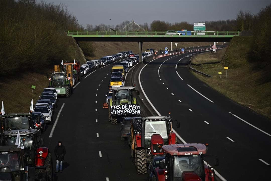 Franse boeren blokkeren de weg met hun trekkers. - Foto: ANP/ JULIEN DE ROSA / AFP