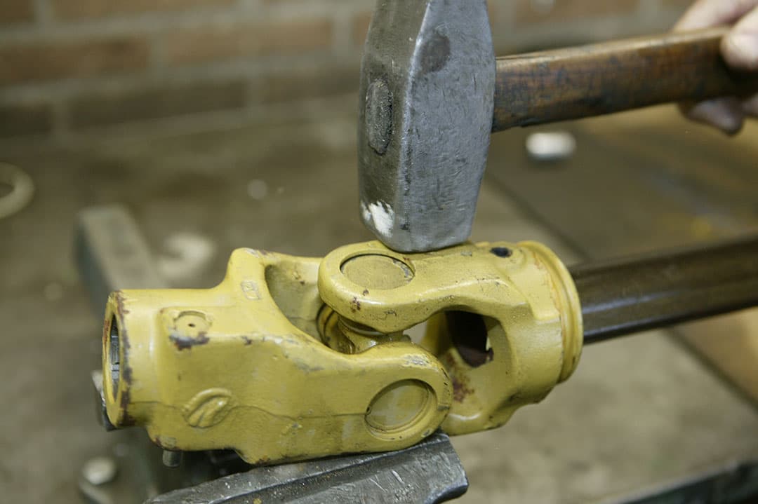 Verwijder één van de borgveertjes met een punttangetje. Geef eventueel een klein tikje erop om de borgveer te ontspannen. Aftakas zoals getoond op de bankschroef leggen en met lichte hamerslagen de twee naaldlagers een stukje eruit drijven. - Foto: Mark Pasveer