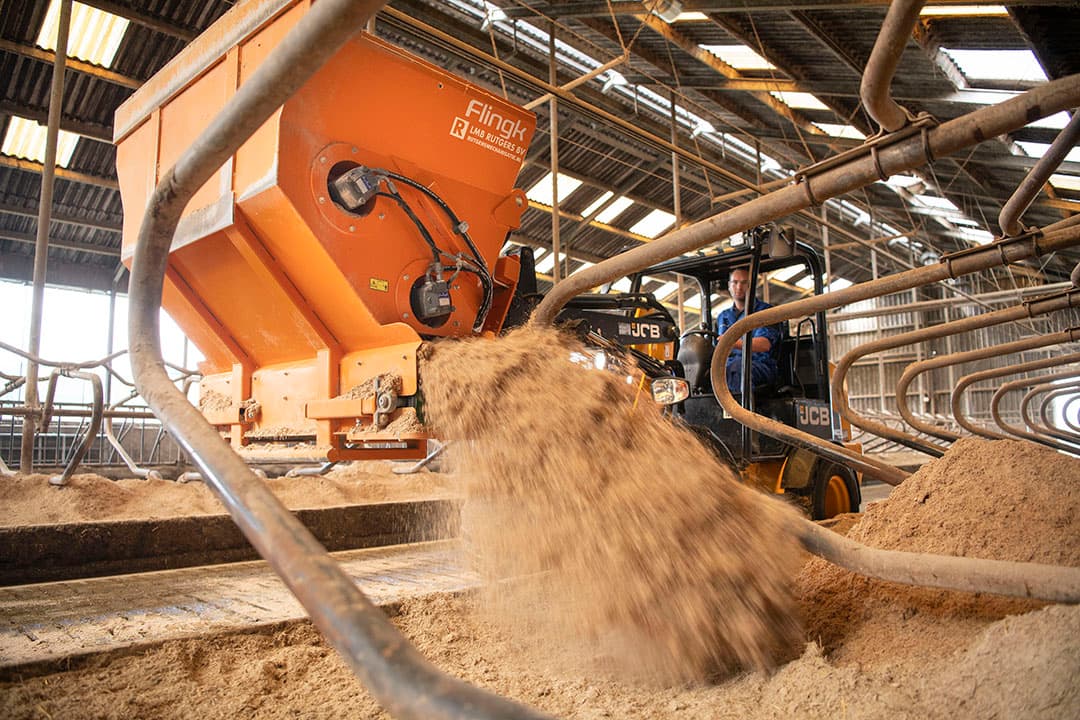Kors Schuitemaker rijdt met zijn shovel en instrooier langs de boxen om ze in te strooien. Met dezelfde instrooier kan hij het product – een mengsel van stro, vlas en kalk – opscheppen in een loods. - Foto's: Mark Pasveer