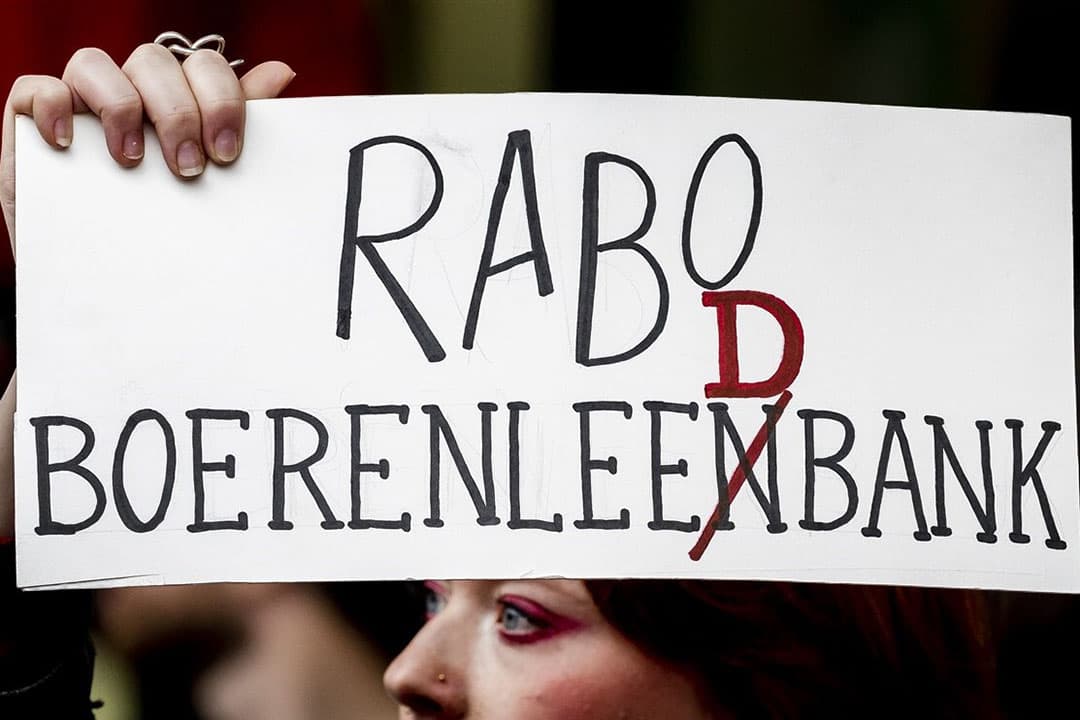 Actievoerders blokkeren de hoofdingang van het hoofdkantoor van de Rabobank tijdens een gezamenlijke actie van XR en Greenpeace. - Foto: ANP