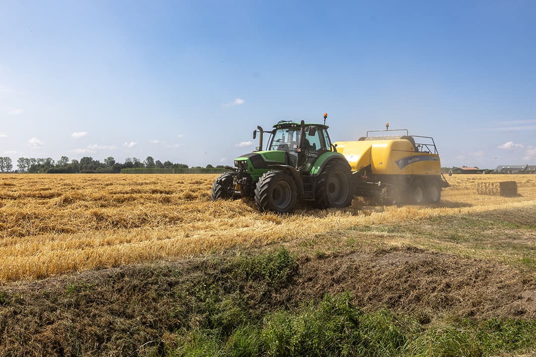 Bij akkerbouwbedrijf Bouman in Poortvliet rijdt de pers achter de maaidorser aan. Voor het stro beter dat het nog even blijft liggen, maar met regen op komst kiest een aantal telers ervoor om toch maar snel op te ruimen. Gemiddeld lijkt de stro-opbrengst ook maar gewoontjes. - Foto: Peter Roek