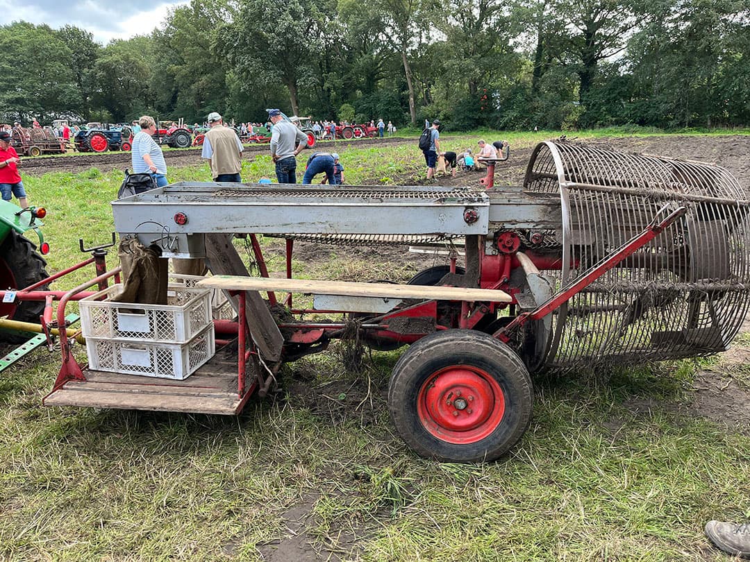 Op een aardappelveld komen rooimachines aan bod. Deze Samro-rooier laat zijn kunsten zien. De aardappels worden voor de draaiende korf gerooid en komen bovenop een naar voren draaiend bandje terecht. Maximaal zes mensen kunnen op de houten bankjes zitten om de aardappels op de buitenste bandjes te leggen. Die bandjes voeren de aardappels naar kisten. Achterblijvende kluiten en loof blijven  liggen op de middenband, en vallen via het glijgootje op de grond.
