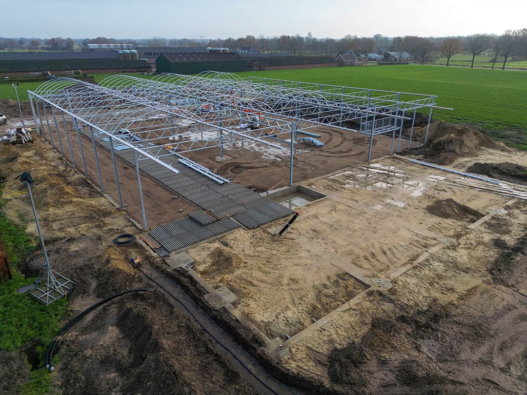 Familie van Esch heeft weer een mooie nieuwe stap met de stalbouw van de koeientuin gezet. Als dak voor deze vrijloop koos de familie voor het bekende serrestalconcept. Medio december werden de bogen door de bouwmedewerkers op hun plek gezet.