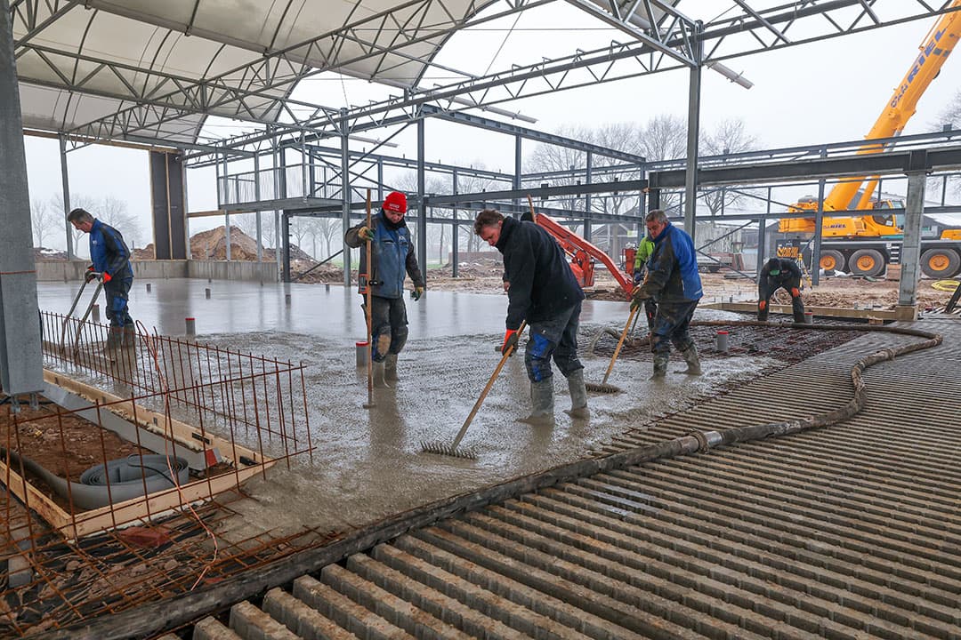 Na het storten wordt het beton gladgestreken. Dit is belangrijk voor de goede afvoer van de urine naar het rioolsysteem dat in de vloer is verwerkt.