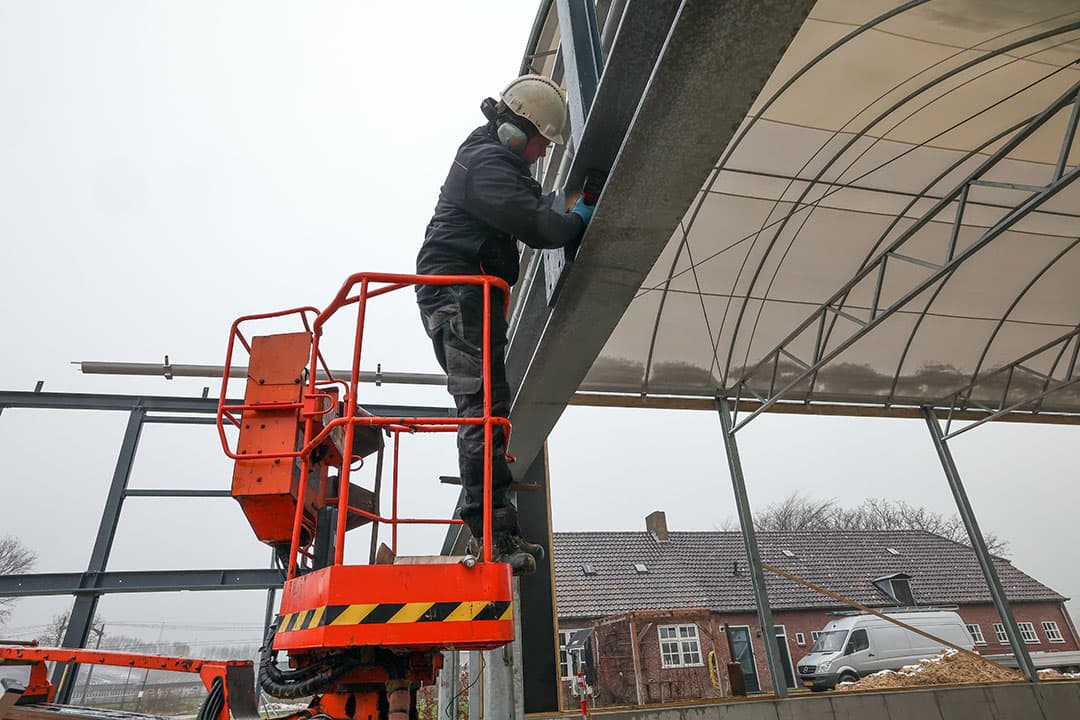Deze medewerker is bezig met het plaatsen van de constructie van het voorgebouw van de koeientuin.