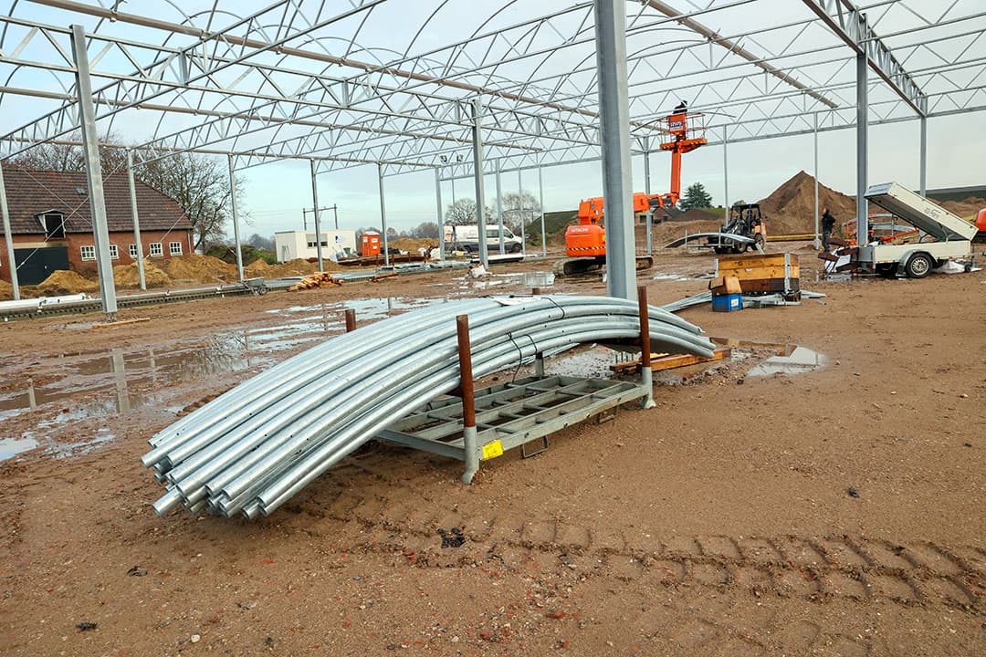 De laatste bogen liggen klaar op een pallet. Het voorgebouw krijgt later nog een serrestaldak, maar daar moet eerst de verdere constructie nog gezet worden.