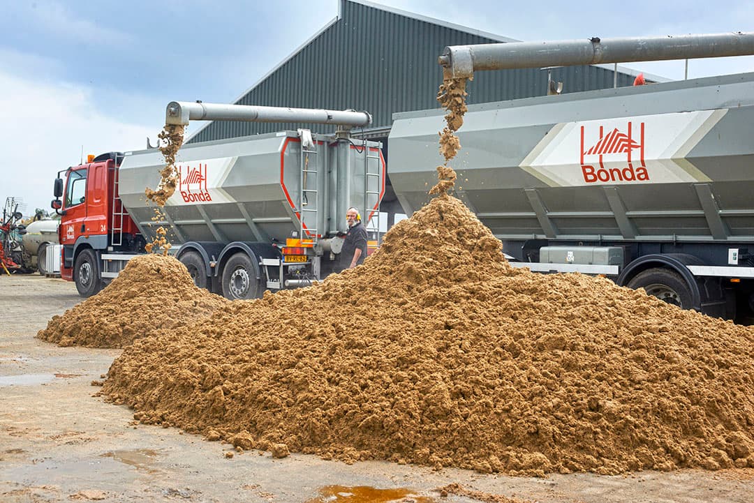 Lossen van Proti+ op een melkveebedrijf. Dit eiwitrijke voer bevat onder andere bierbostel, als restproduct van bier brouwen. En tarwegistconcentraat dat vrijkomt bij winning van bio-ethanol uit tarwe. - Foto: Van Assendelft Fotografie