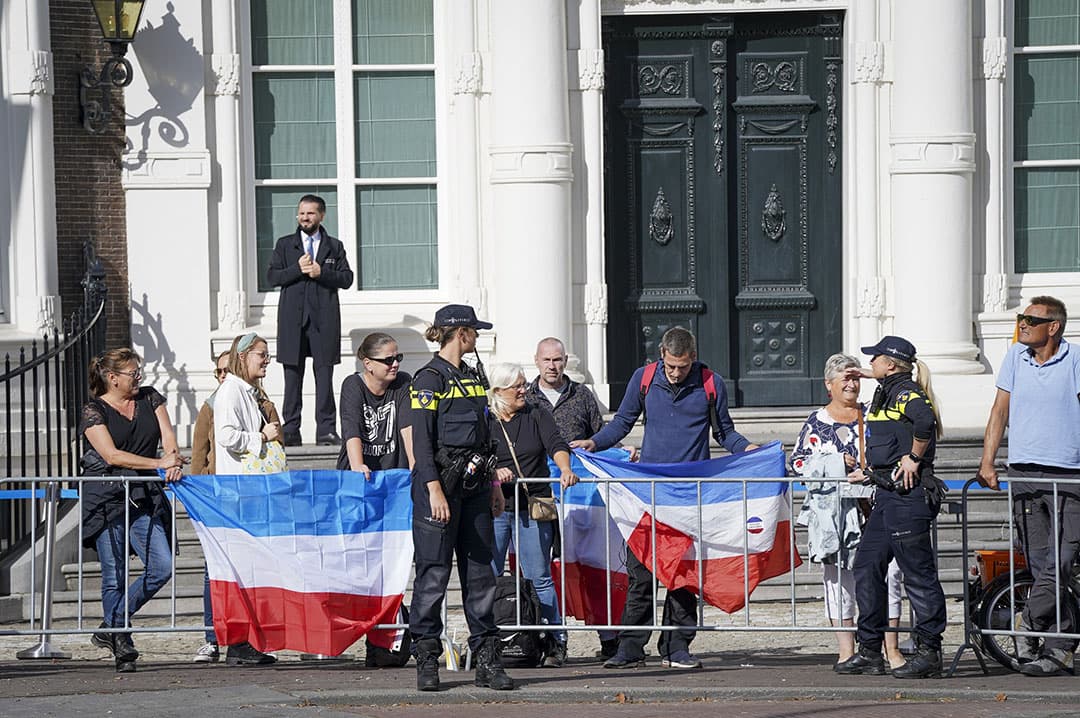 Toeschouwers in Den Haag met omgekeerde Nederlandse vlaggen voorafgaand aan Prinsjesdag. - Foto: ANP