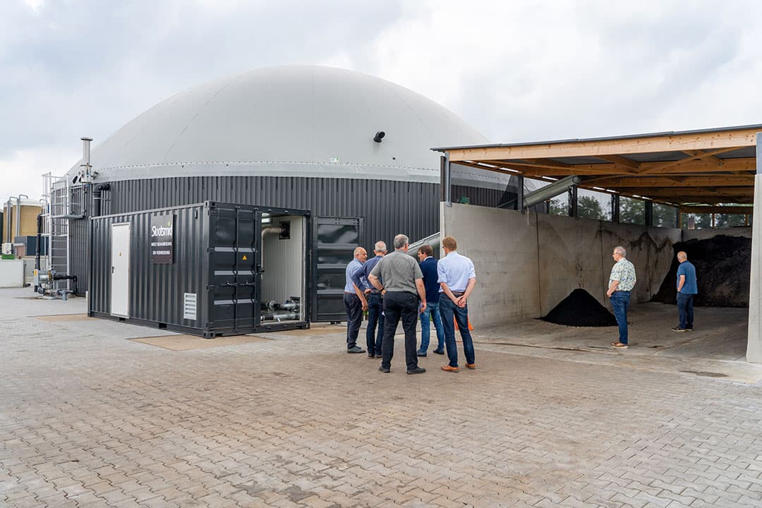 De bezoekers van de open dag staan voor de silo met daarin de dikke fractie van het digestaat. De scheider zit in de container links. - Foto's: Jan Willem Schouten