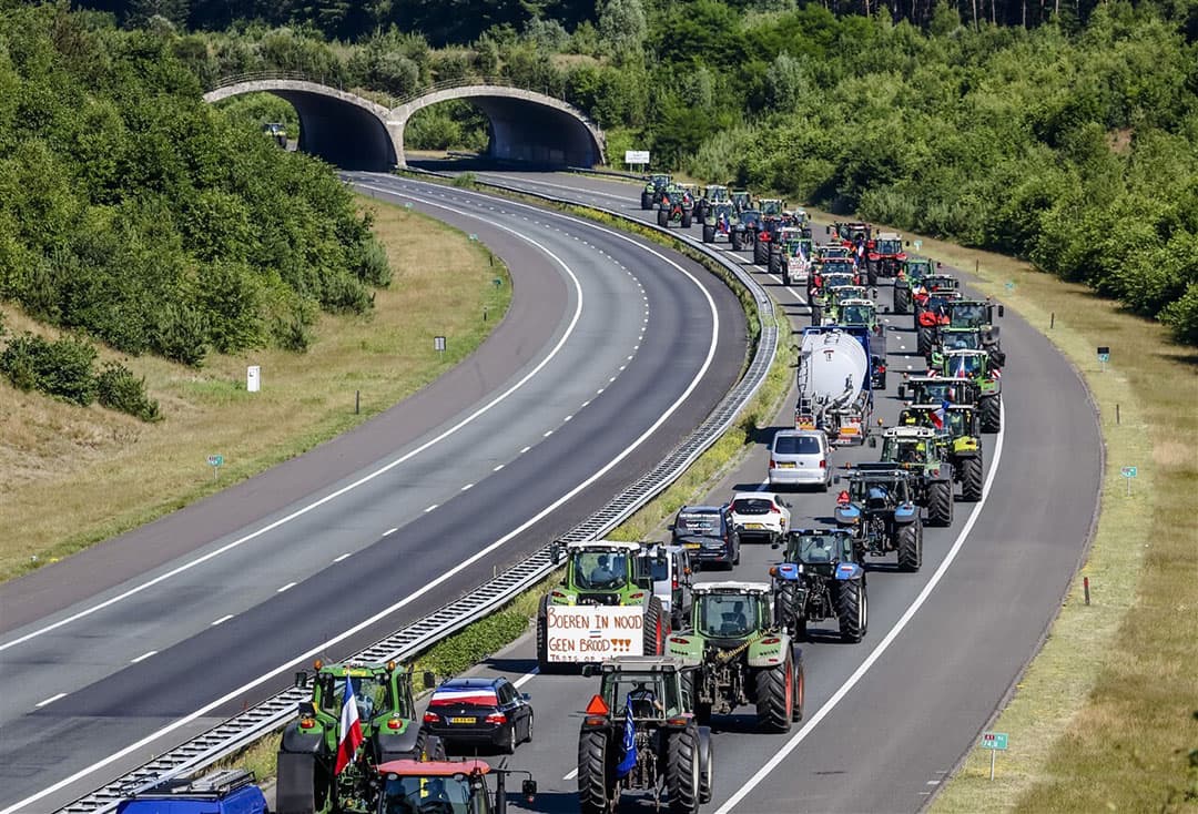 Boeren reden na de bijeenkomst in Stroe met trekkers over de snelweg A1 naar huis. - Foto: ANP