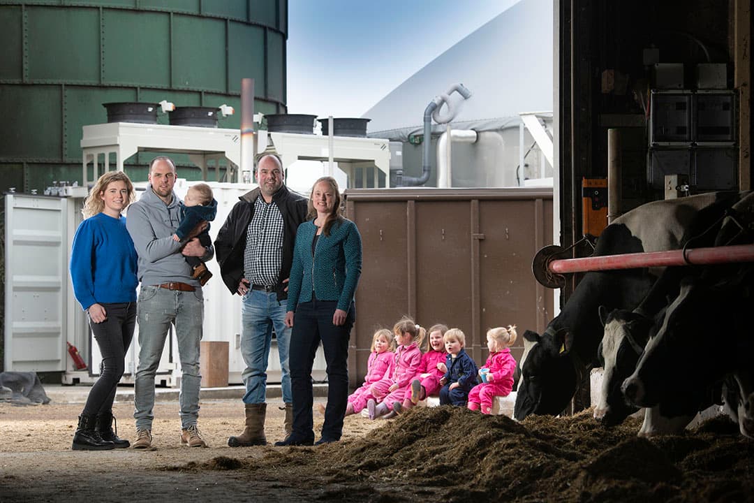 Familie Janssen met op de achtergrond de mono-mestvergister. V.l.n.r. Silvana (30), Thijs (35), Guus (0), Luuk (38), Foke (38), Imke (3), Benthe (5), Maud (6), Huub (2) en Madée (2)