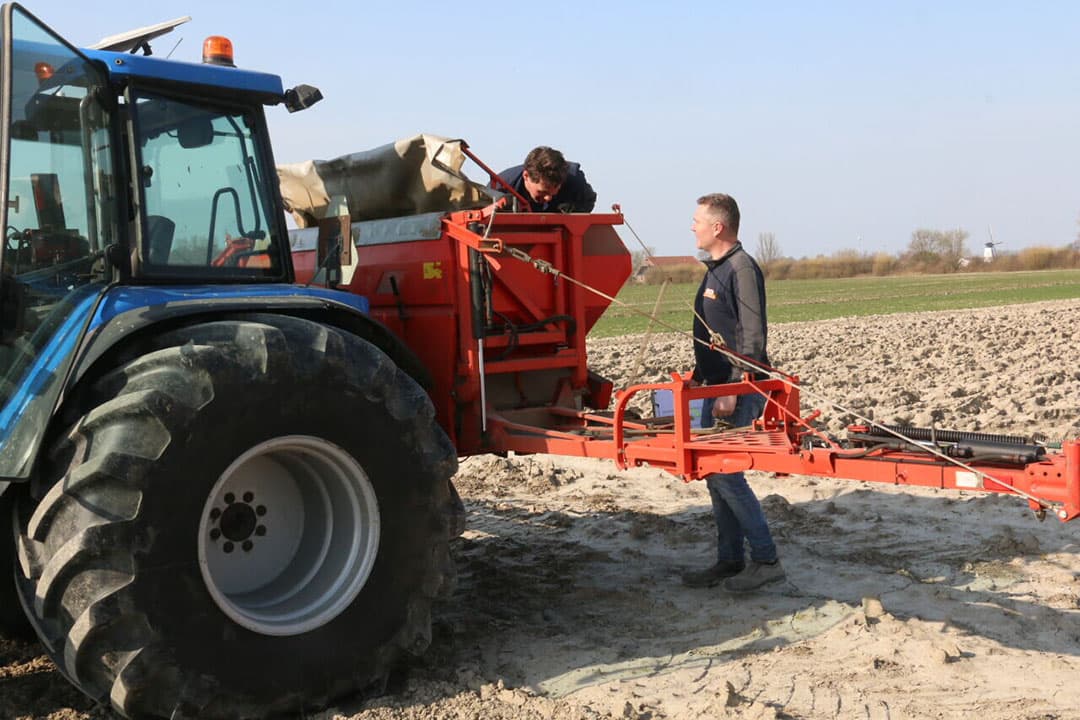 Voor een bemesting wordt gegeven is eerst nog even de verdeling in de kunstmeststrooier gecontroleerd. Er wordt voldoende in de bak gedaan voor de te bemesten veldjes. Vaak gaat het om kleine hoeveelheden, maar dat moet wel goed verdeeld liggen. - Foto's: Anton Dingemanse