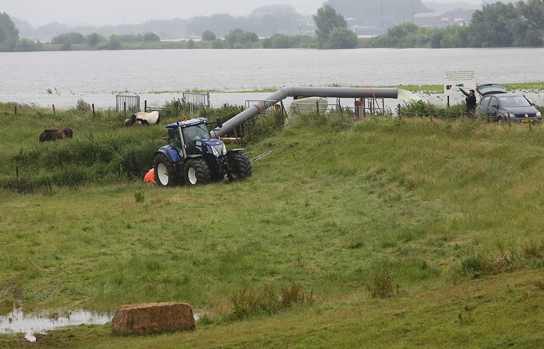 Boeren pompen water uit de uiterwaarden bij Dodewaard bij zomers hoogwater. In de toekomst zal vaker wateroverlast voorkomen. Akkerbouwgewassen in uiterwaarden wordt steeds riskanter. - Foto: VidiPhoto