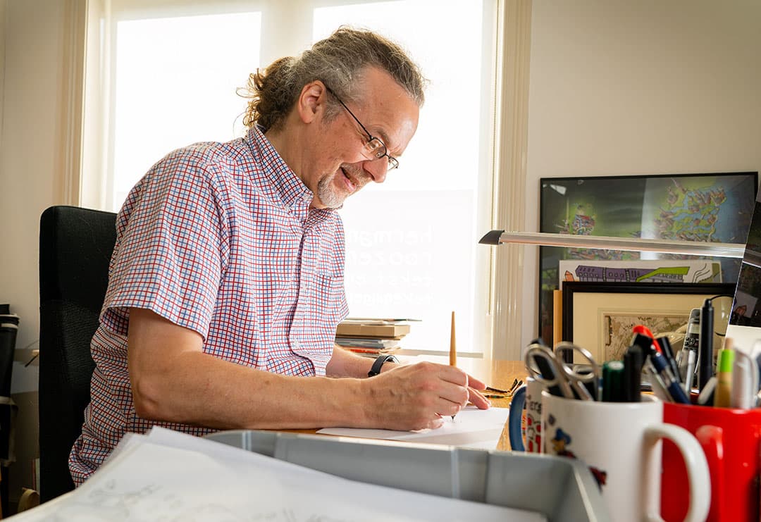 Herman aan zijn tekentafel. Elke strip begint op een vel papier en eindigt digitaal op het computerscherm. - Foto: Jan Willem Schouten
