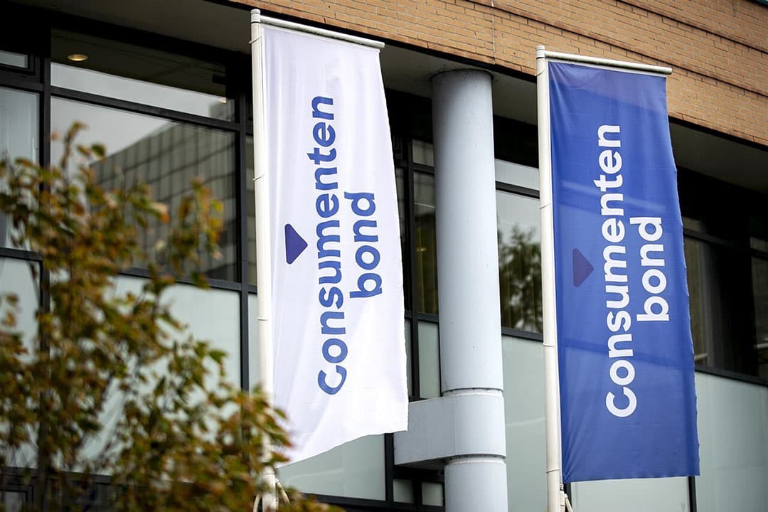 Logo op vlaggen bij het hoofdkantoor van de Consumentenbond in Den Haag. - Foto: ANP