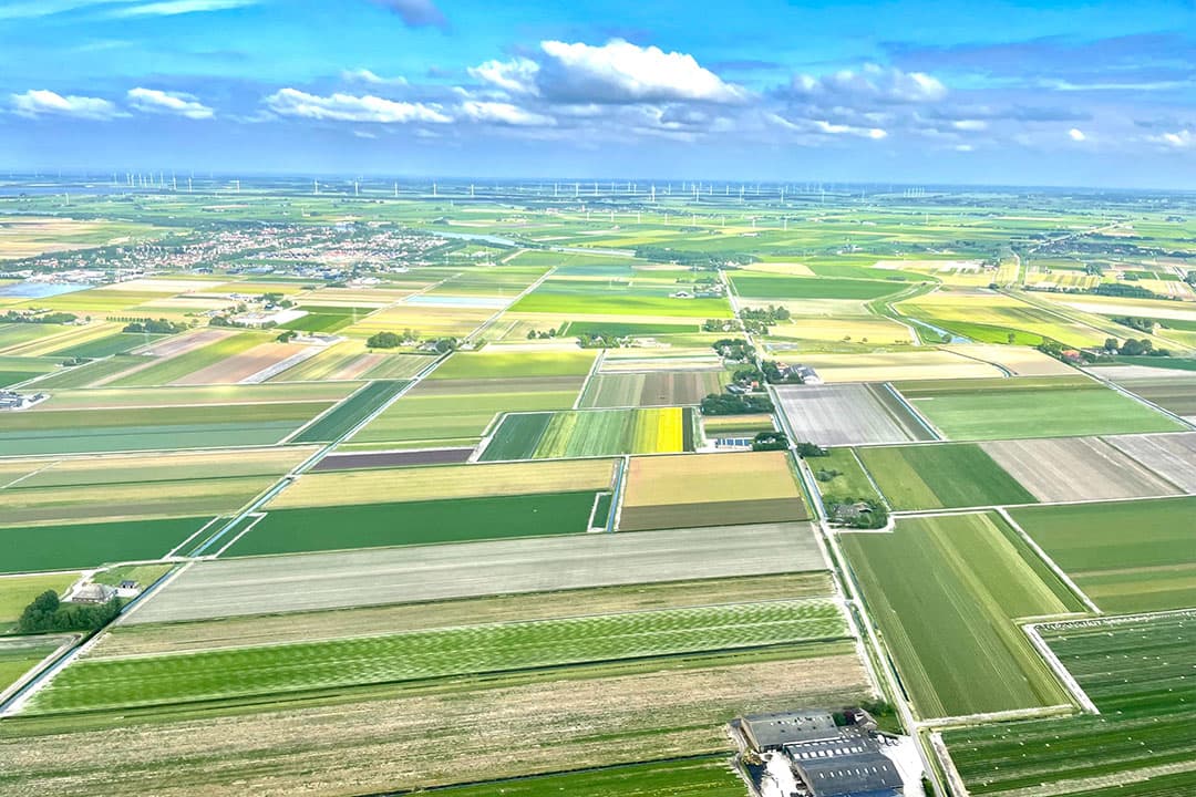 Landbouwgrond in de provincie Noord-Holland, met op de achtergrond windmolens. - Foto: Martijn ter Horst