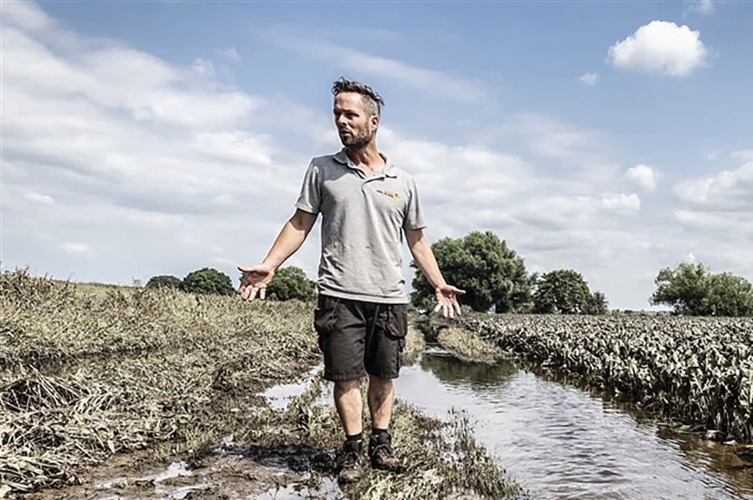 Een akkerbouwer neemt de schade op die het gevolg is van overstromen van de Maas. - Foto: ANP