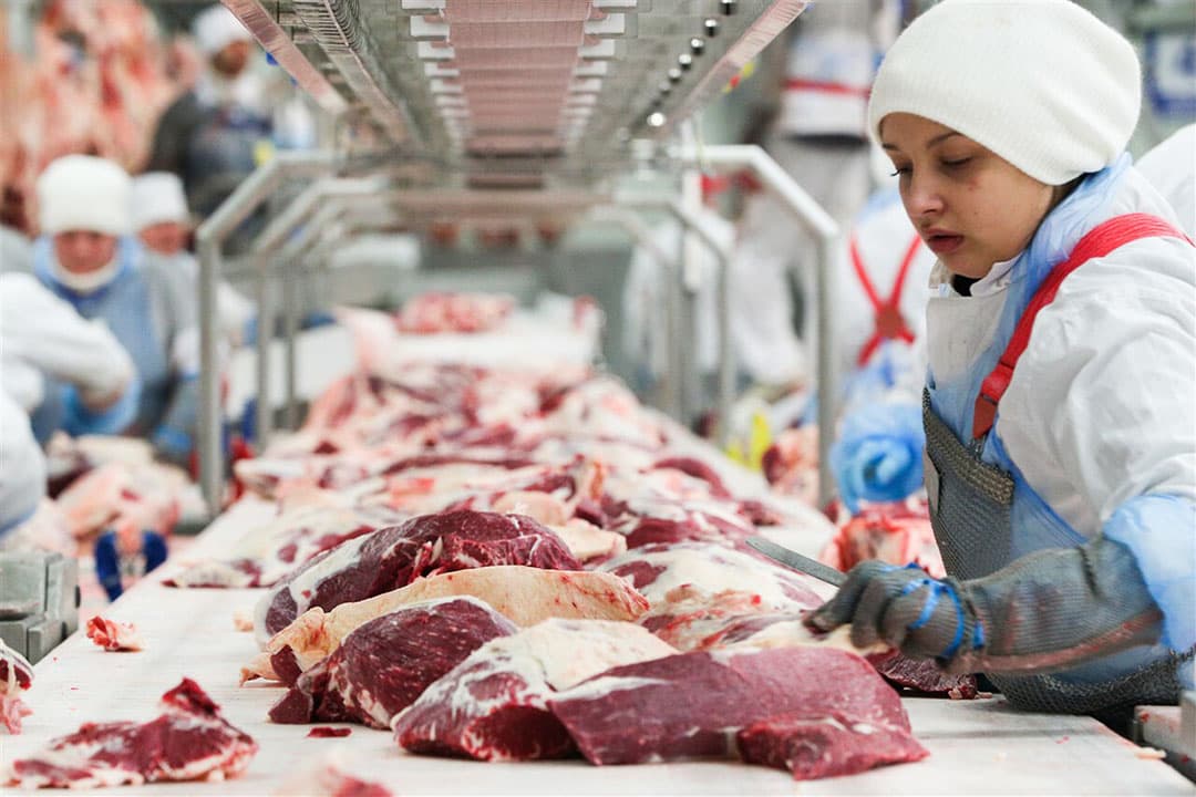 Een slager bezig met de verwerking vlees. - Foto: ANP