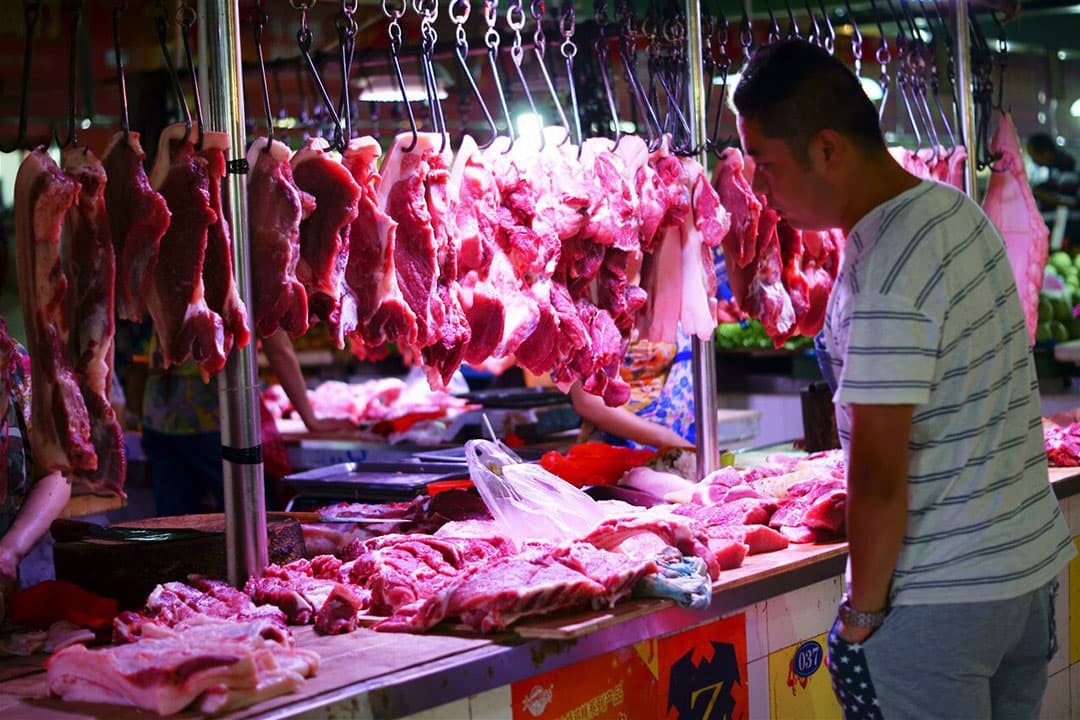 De verkoop van varkensvlees op een Chinese markt. - Foto: ANP