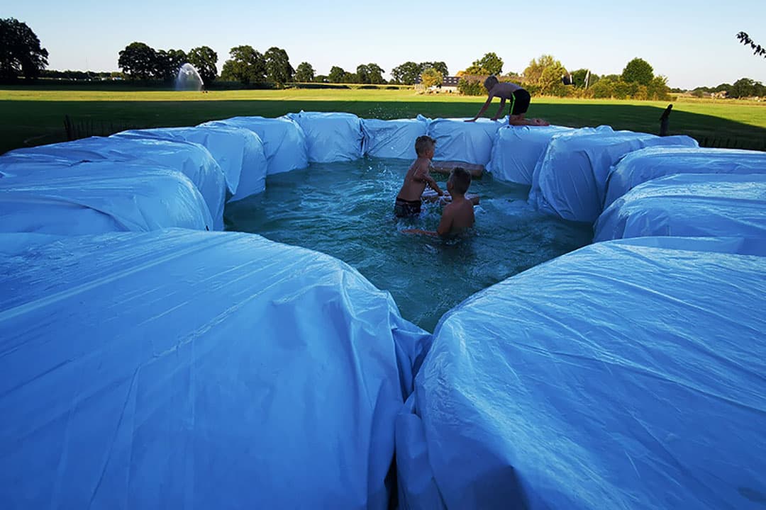Geertjan Kloosterboer bouwde van ronde balen en kuilplastic een groot privézwembad. - Foto: Fam. Kloosterboer