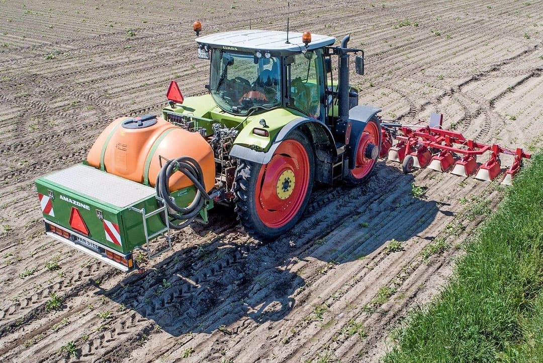 Hier wordt het werk uitgevoerd door zzp'er Jan de Gorter voor loonwerker Van Steen. Het is van belang om de zaaisporen te volgen, zegt De Gorter. Hij gebruikt een witte aanwijsstaaf voor de spuit, om de exacte breedte langs de rijen te rijden.