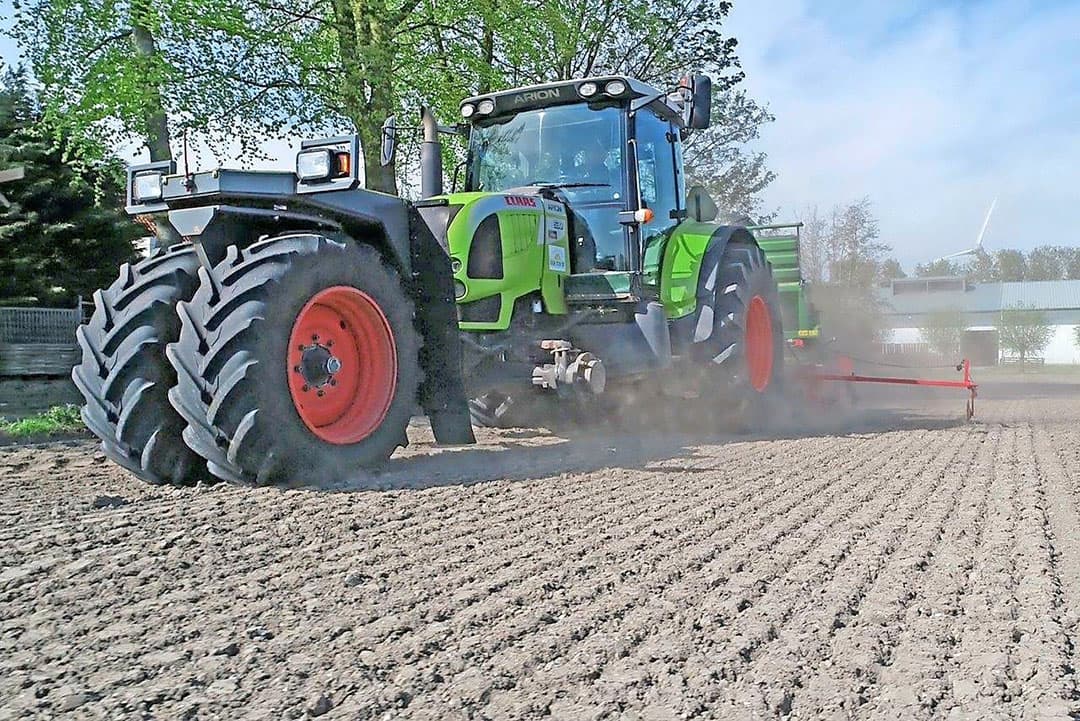 Peter van Gerner heeft zich goed gewapend tegen het stof waarmee hij achter op de zaaimachine te maken heeft. Hij draagt een uitgebreid stofmasker. Anders zou hij dit werk niet naar behoren kunnen uitvoeren.