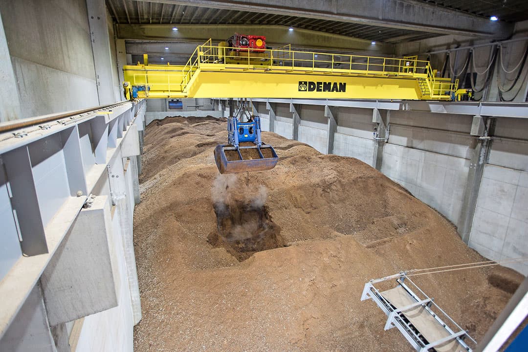 De opslagloods voor kippenmest. In totaal kan BMC een voorraad van 30.000 ton pluimveemest. Geautomatiseerde kranen scheppen de mest naar de transportband. - Foto: Peter Roek