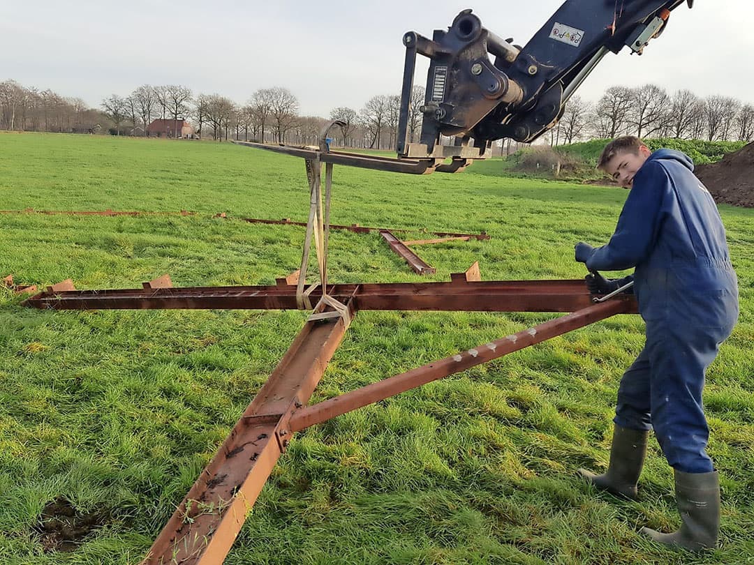 De spanten liggen inmiddels klaar in het grasland. Opvallend is dat Smale koos voor tweedehands spanten. Die zijn van een buurman. Hier liggen de spanten los. Ze moeten nog met bouten in elkaar gezet worden.
