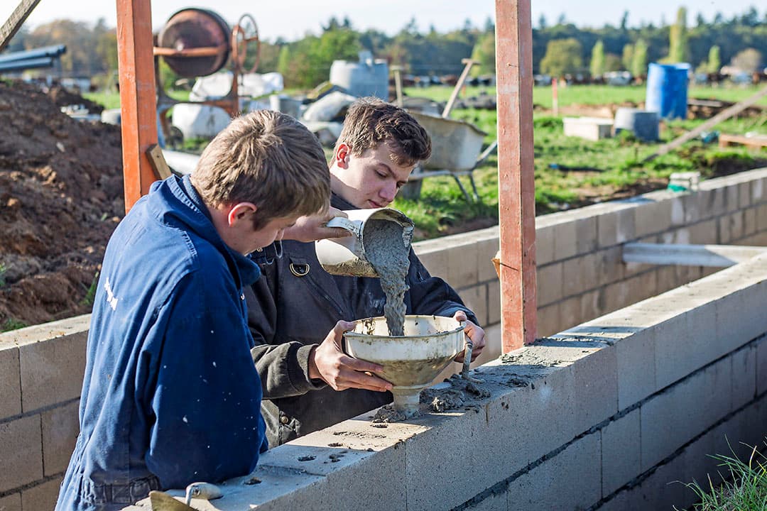 Het werk vordert gestaag. Op de achtergrond zijn de werktuigenloods (links) en de jongveestal te zien.